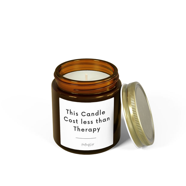 Amber glass candle with "This Candle Cost less than Therapy" label and gold lid.