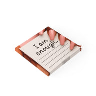 Pink manicured fingers holding a square sticky note pad with 