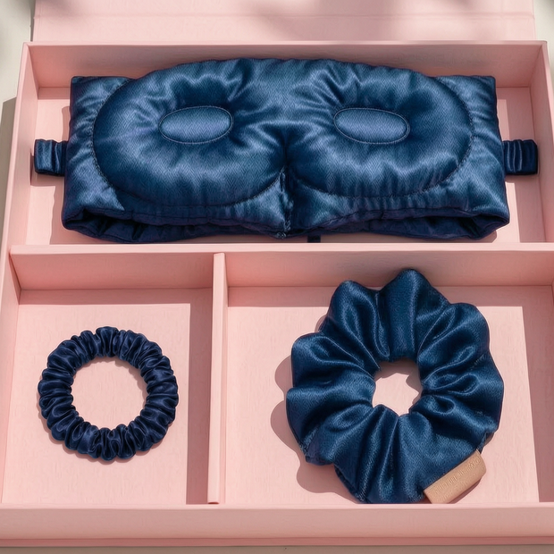 Navy blue 3D mulberry silk sleep mask and two matching silk scrunchies inside a luxury pink gift box.