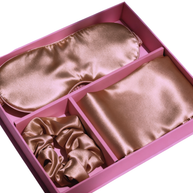 Light gold satin pillowcase, eye mask, and scrunchie in a pink gift box with dividers.