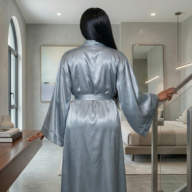 Woman from behind wearing a full-length, silky gray satin kimono robe with wide sleeves and a waist tie.