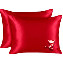 Two vibrant red satin pillowcases, one with a white crown and script 